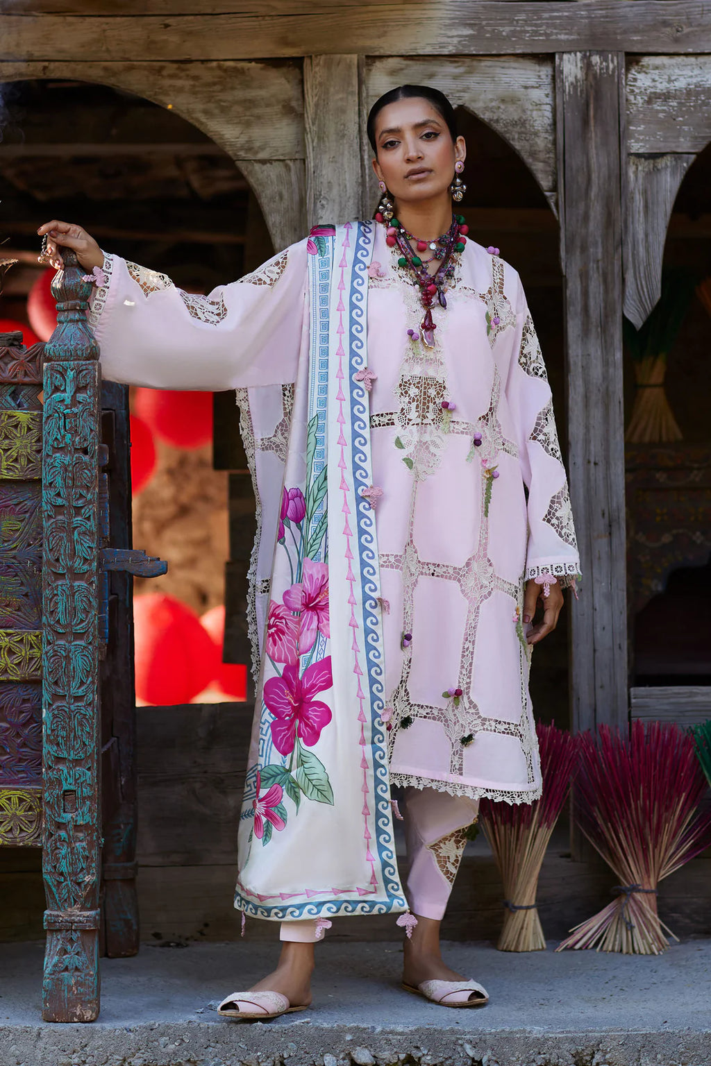 Woman in traditional embroidered outfit standing in front of a wooden door.