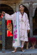 Woman in traditional embroidered outfit standing in front of a wooden door.