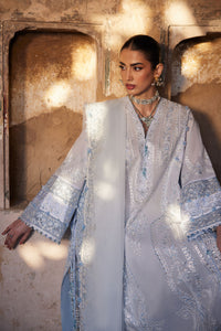 Woman wearing a light blue embroidered traditional outfit in a warm-toned setting