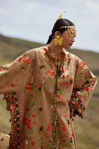 Woman in an ornate embroidered outfit with a scenic background