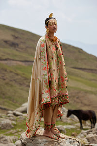 Woman in traditional attire standing on a rocky outcrop with a horse in the background