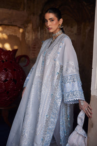 Woman wearing a light blue embroidered traditional outfit with a dark background