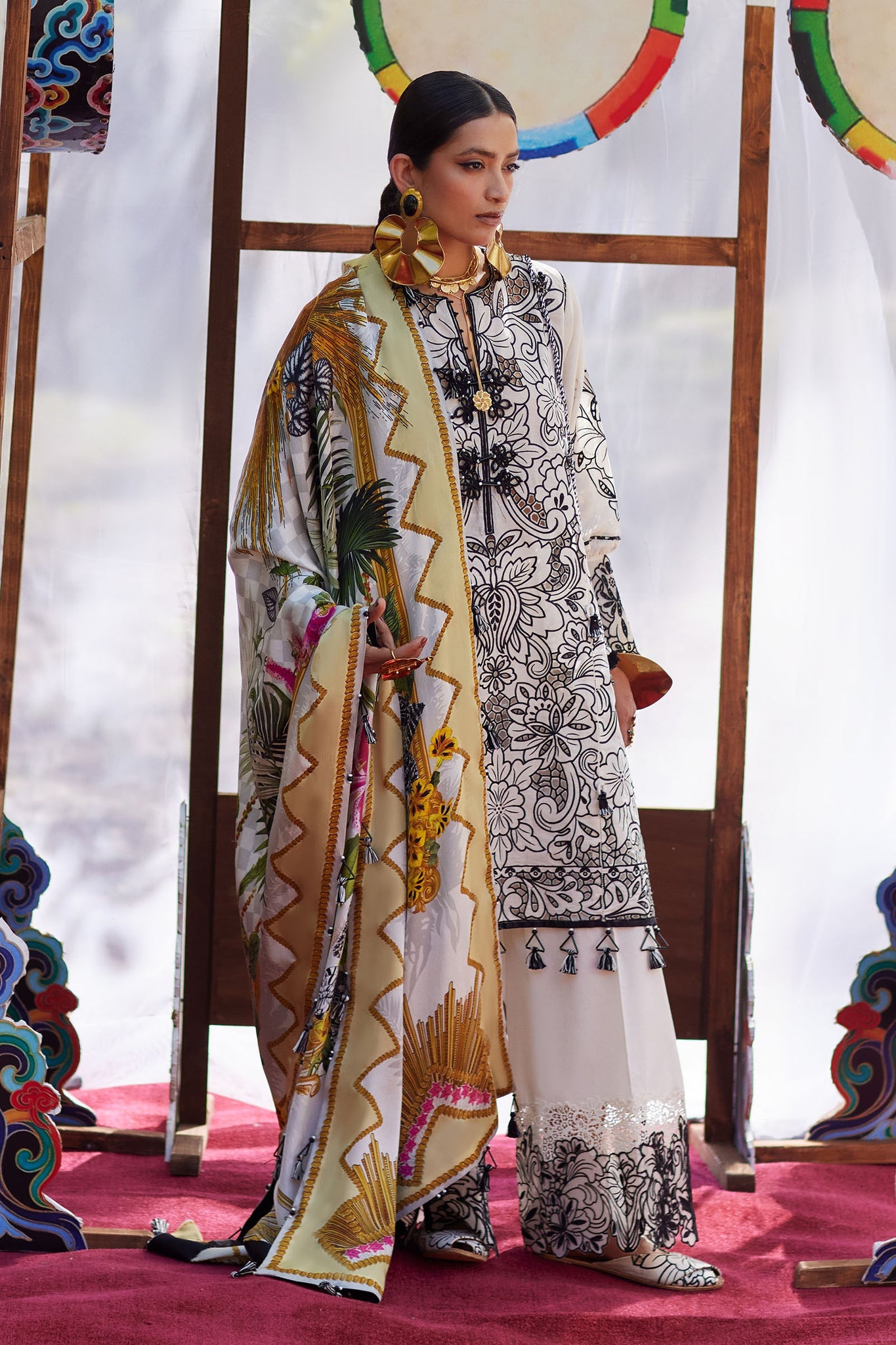 Woman in traditional attire with a colorful scarf against a decorative background