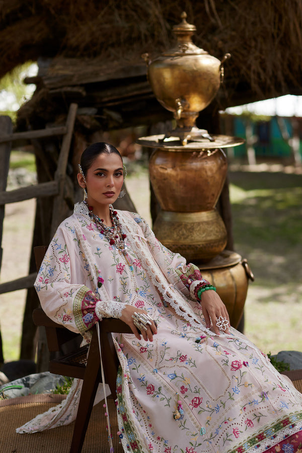 Woman in a floral dress sitting on a wooden chair outdoors with traditional decor.