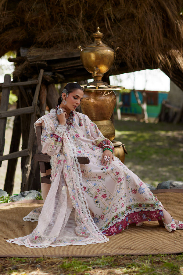 Woman in a floral dress sitting on a mat with a traditional setting in the background