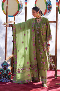 Woman in a green embroidered traditional outfit with decorative drums in the background