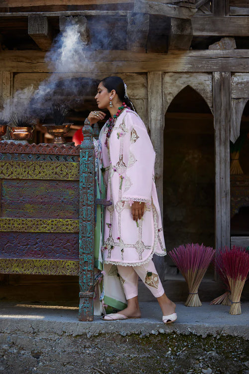 Woman in traditional attire standing in front of a temple with incense sticks.