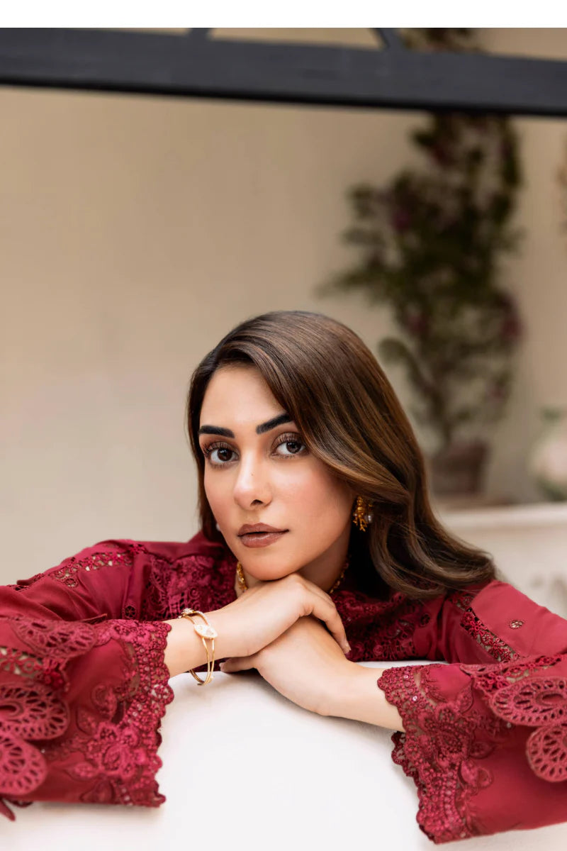 Woman in a red lace top sitting indoors with a neutral background