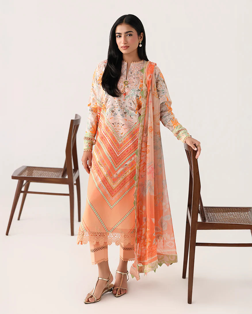 Woman wearing a peach-colored traditional outfit with a matching dupatta, standing between two wooden chairs on a white background.