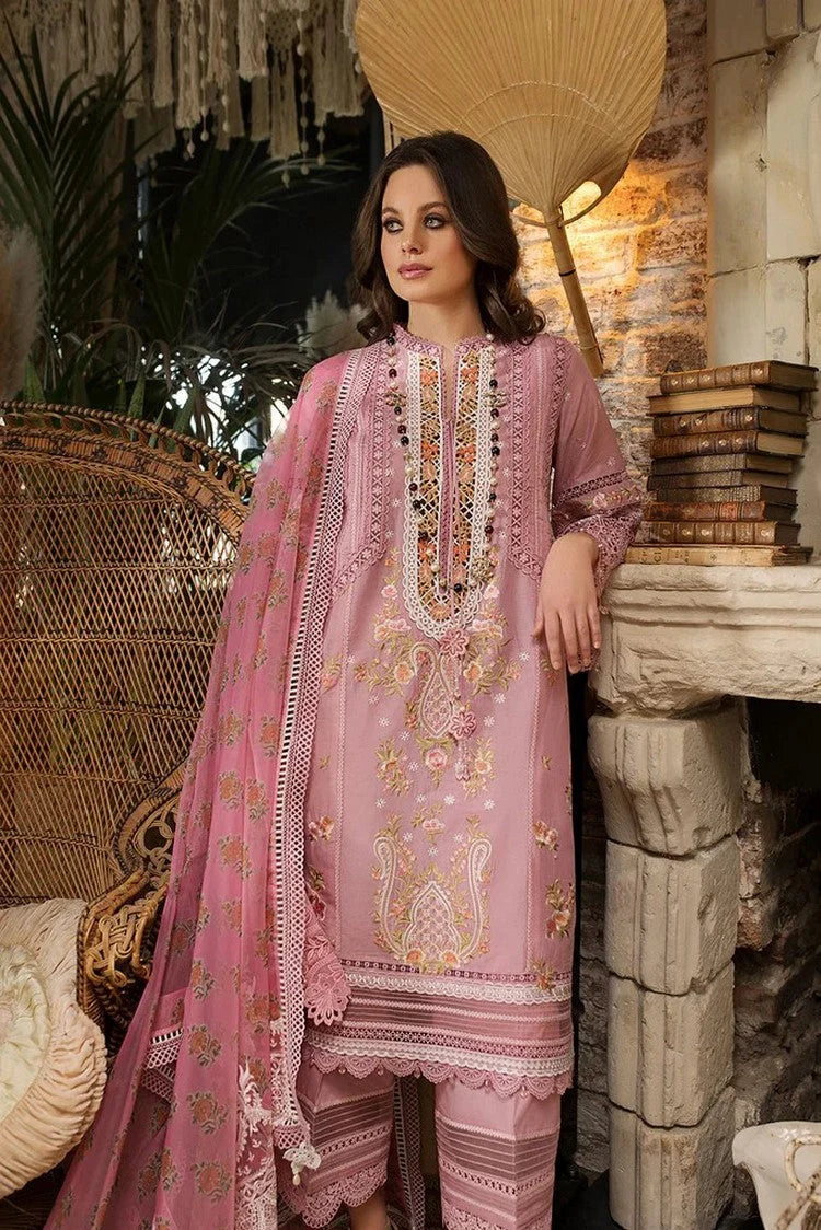 Woman in a pink embroidered traditional outfit standing in a decorative setting with books and plants.