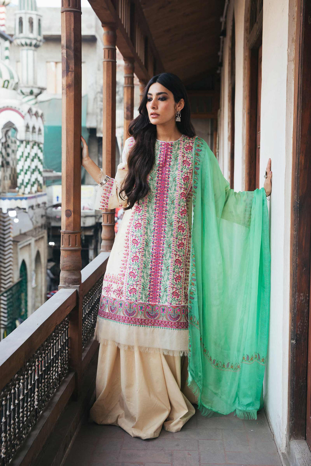 Woman in traditional outfit with floral patterns on a balcony