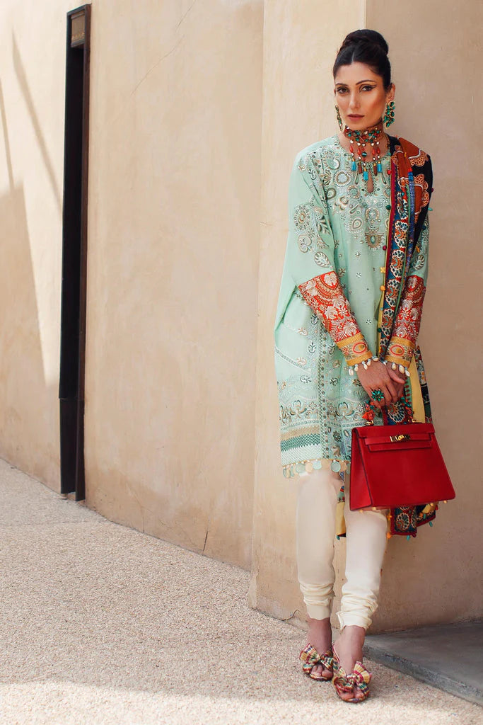 Woman in traditional outfit with a red handbag against a beige wall.