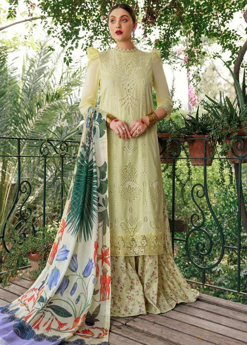 A woman models a traditional three-piece salwar kameez suit in pale yellow with intricate embroidery, paired with a multicolor floral printed dupatta, set against a lush garden background.