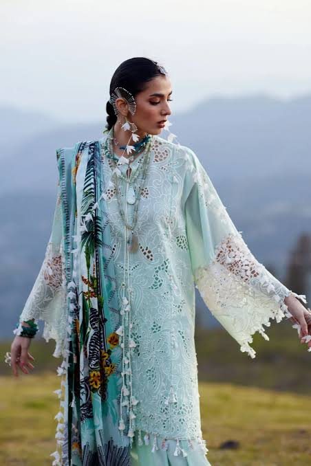 Woman in a light green embroidered dress with a floral shawl in a field