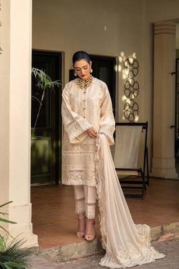 Woman in a traditional outfit standing in an indoor setting with decor elements.