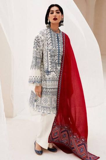 Woman wearing a traditional outfit with a white and black patterned top, white pants, and a red dupatta.