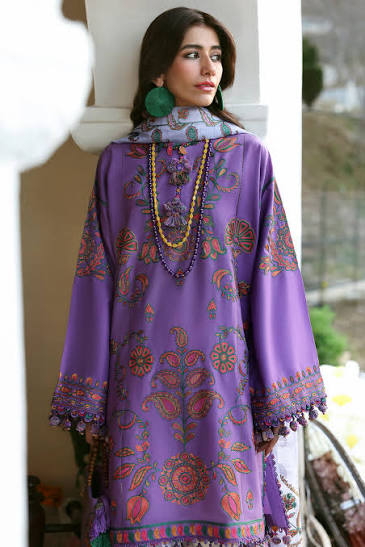 Woman wearing a purple embroidered dress with colorful patterns.