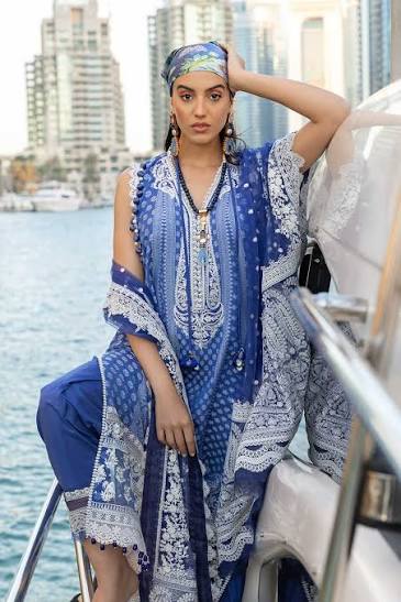 Woman in a blue and white patterned outfit on a boat with city skyline in the background