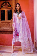 A woman models a traditional three-piece salwar kameez suit in light purple with white floral embroidery and a matching sheer dupatta, set against a warm terracotta wall and carved wooden door.