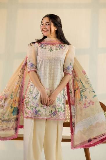 Woman wearing a floral embroidered outfit with a colorful dupatta indoors.