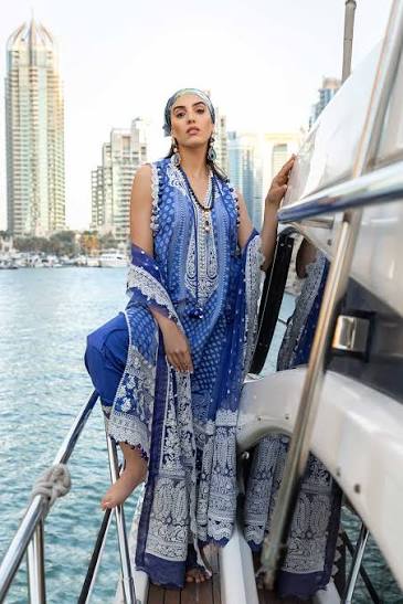 Woman in a blue and white patterned outfit on a boat with city skyline in the background