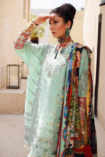 Woman wearing a light green embroidered outfit with a colorful scarf outdoors.