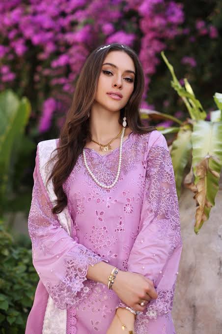 Woman in a pink embroidered outfit with a floral background