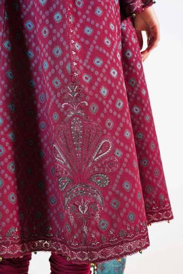 A close-up of a magenta pink embroidered kurta featuring intricate silver and blue paisley and floral patterns, paired with matching pink trousers.