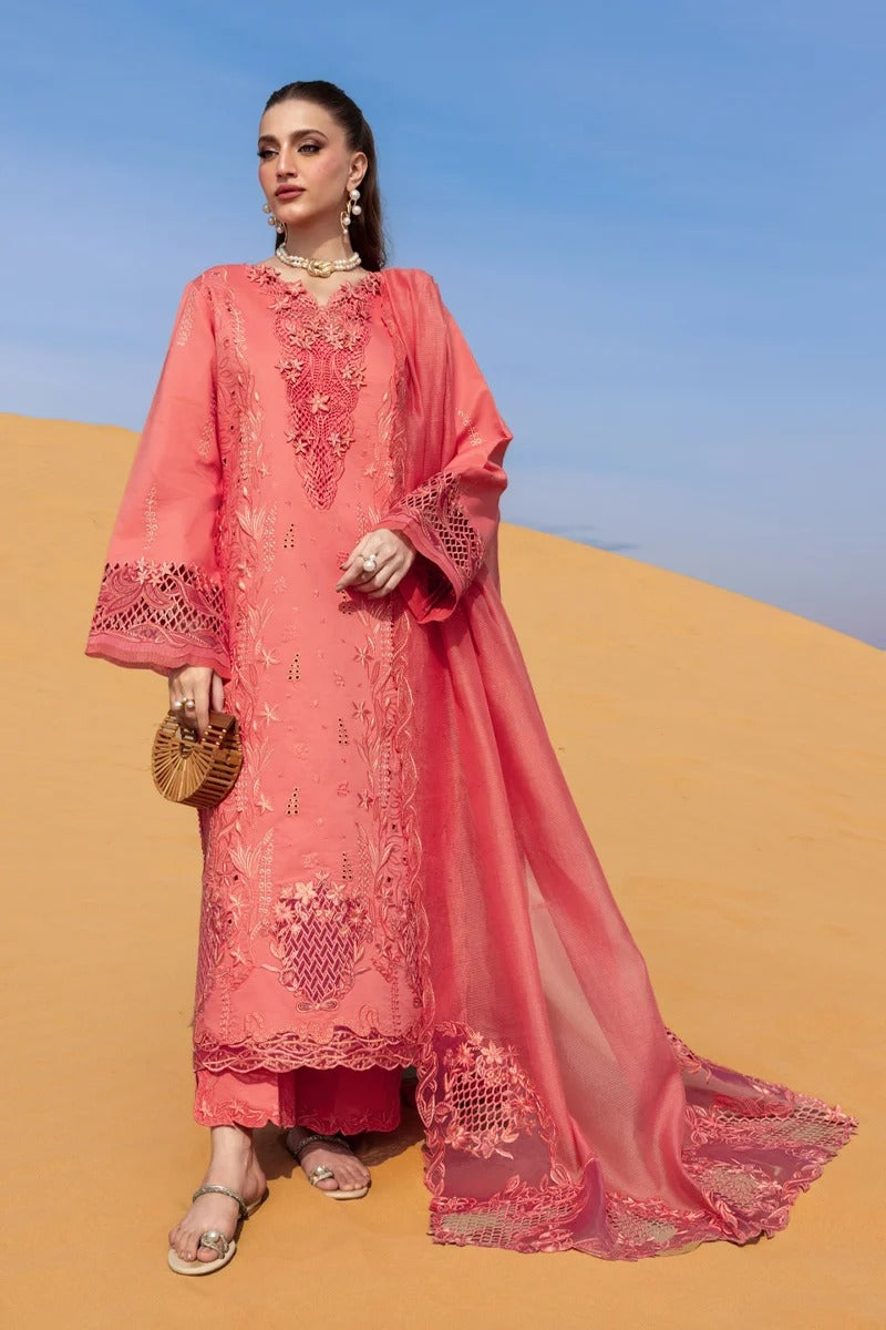 Woman in a pink embroidered outfit standing on sand dunes with a blue sky.