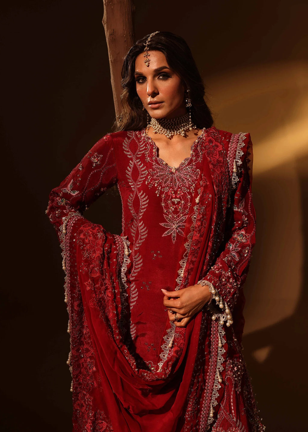 Woman wearing a red embroidered traditional outfit against a dark background