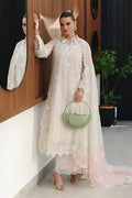 A woman models a traditional cream-colored embroidered kurta set with a matching sheer dupatta and light pink gradient underlayer, holding a sage green handbag.