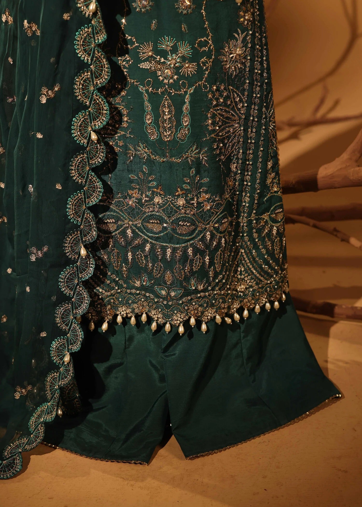 Green embroidered fabric with intricate patterns on a brown background