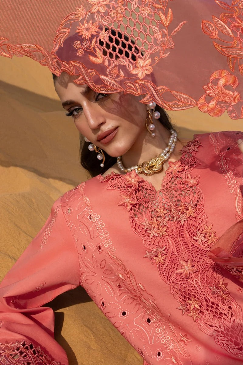 Woman wearing a pink embroidered outfit with a matching headscarf against a desert background