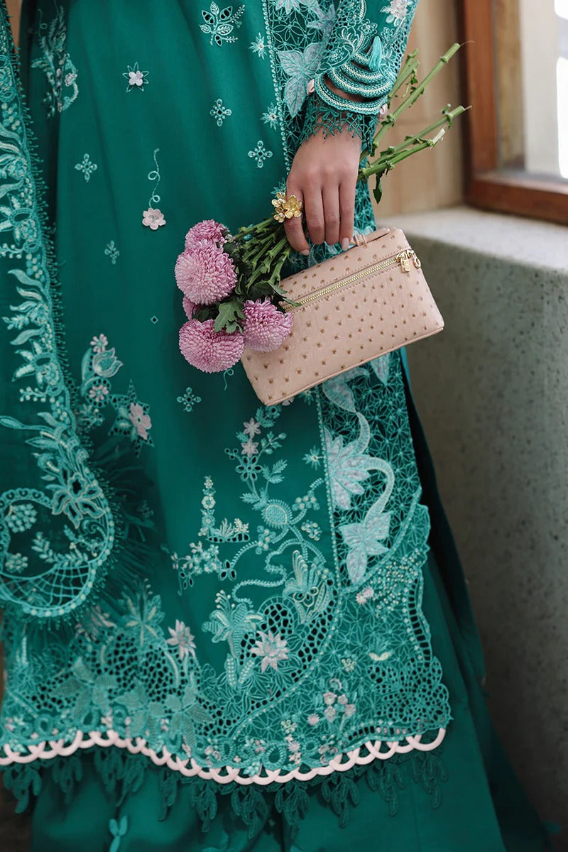 Person wearing a green embroidered dress holding a pink clutch and flowers.