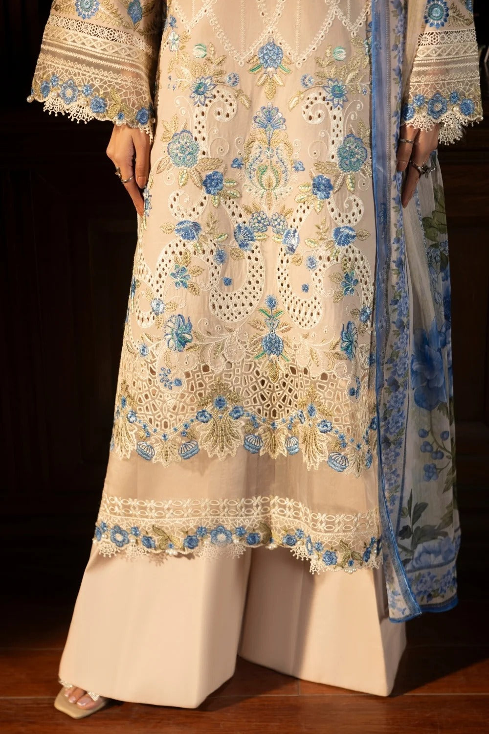 Beige embroidered outfit with blue floral patterns on a dark background