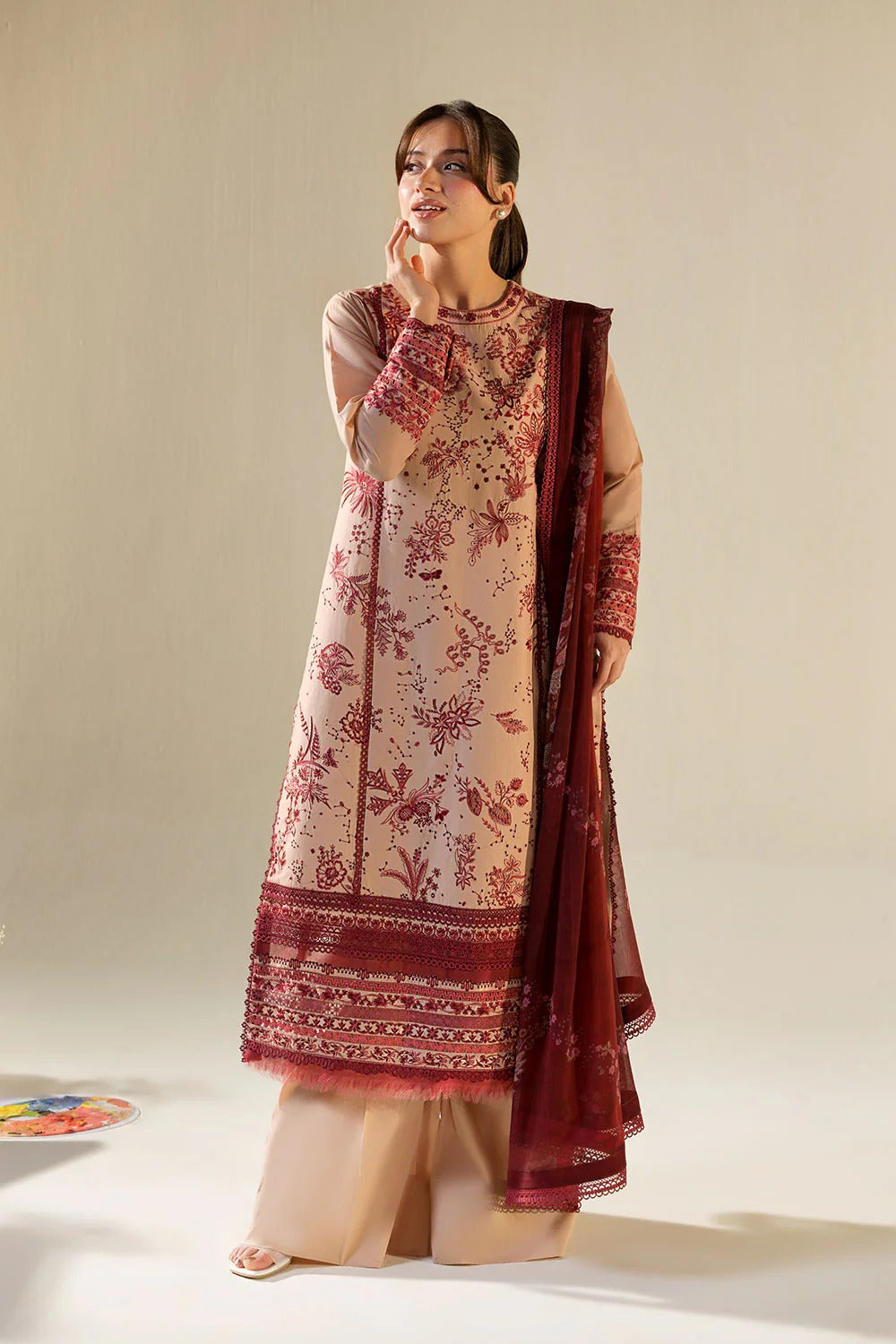Woman wearing a traditional outfit with a floral design on a plain background