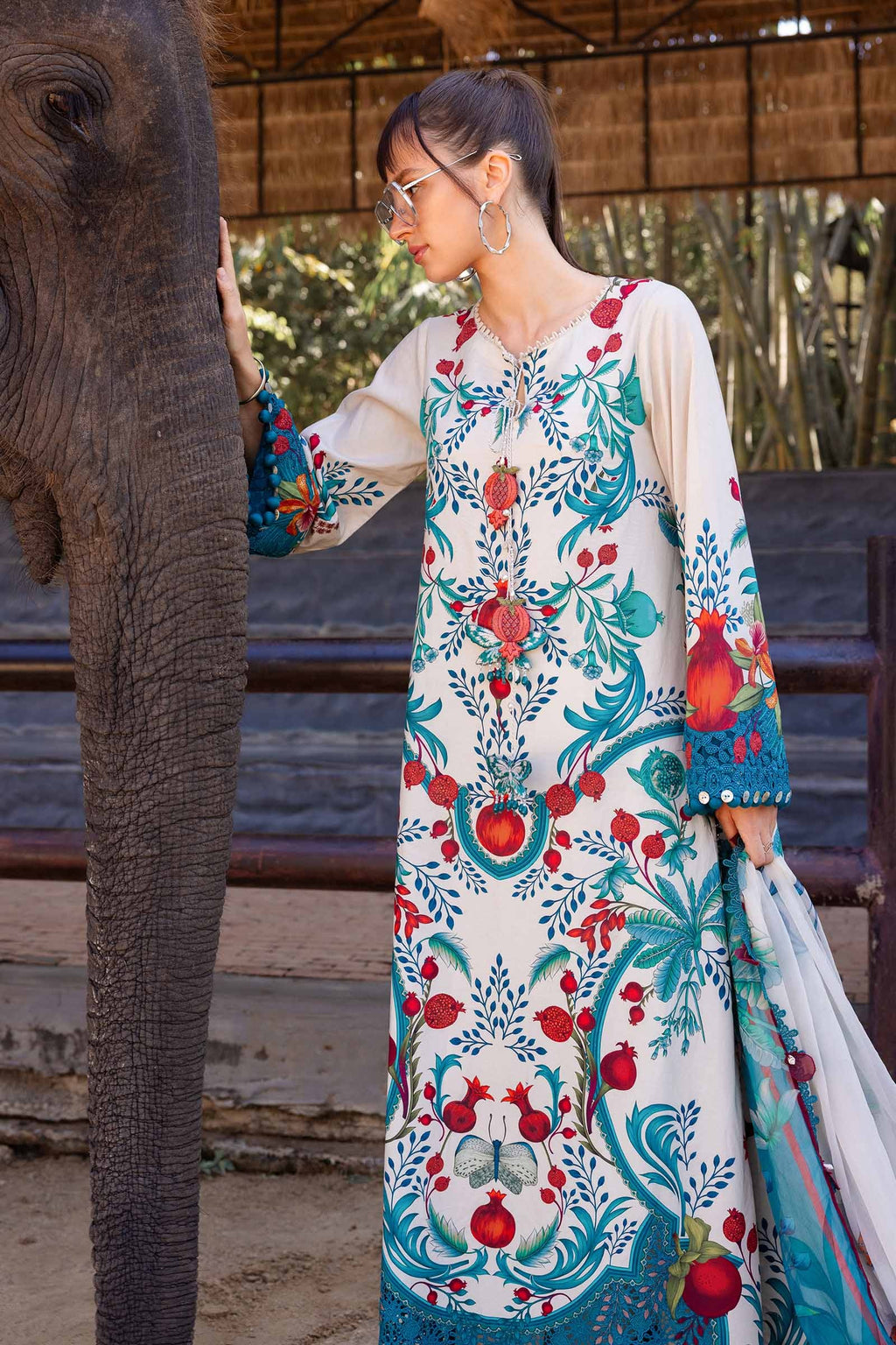 Woman in a colorful floral dress interacting with an elephant.