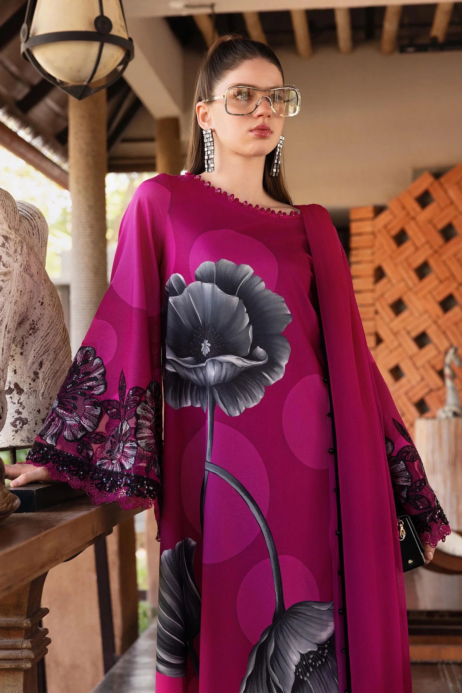 Woman wearing a vibrant pink dress with floral patterns in an outdoor setting