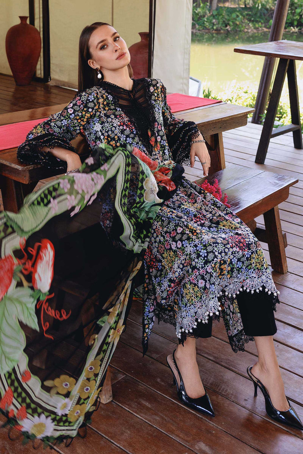 Woman in a floral dress sitting on a wooden bench outdoors.