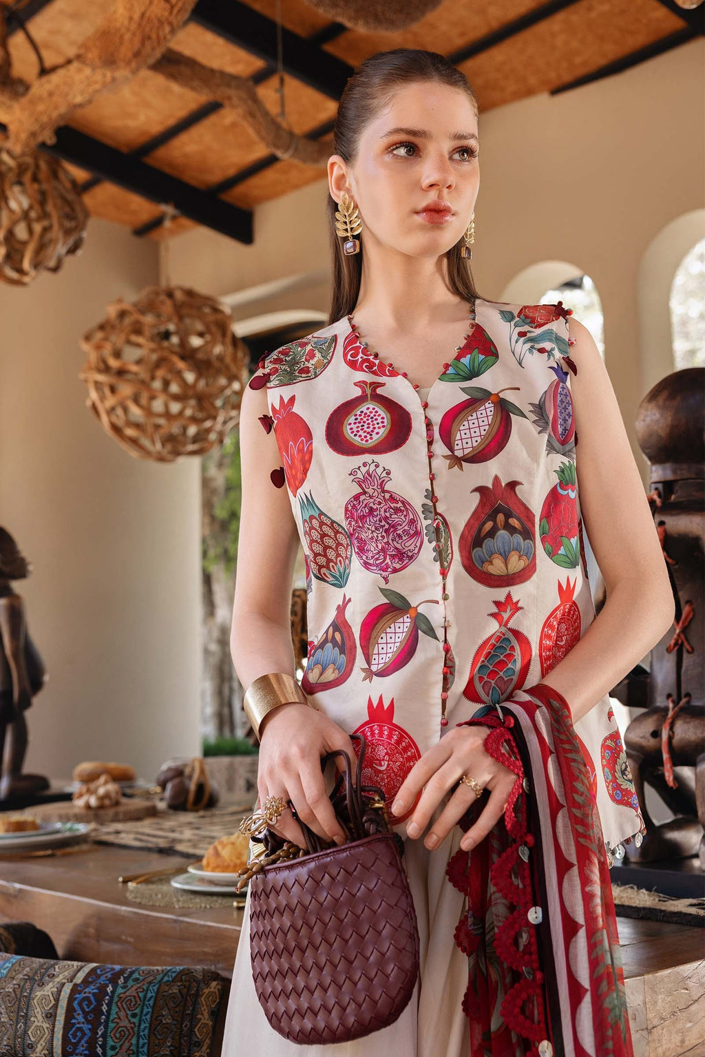Woman wearing a sleeveless dress with pomegranate pattern in an indoor setting