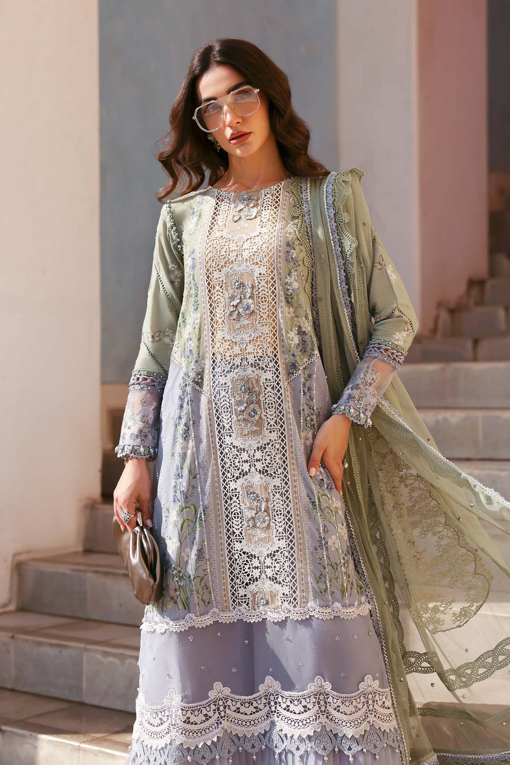 Woman in a traditional outfit with intricate patterns standing on steps.