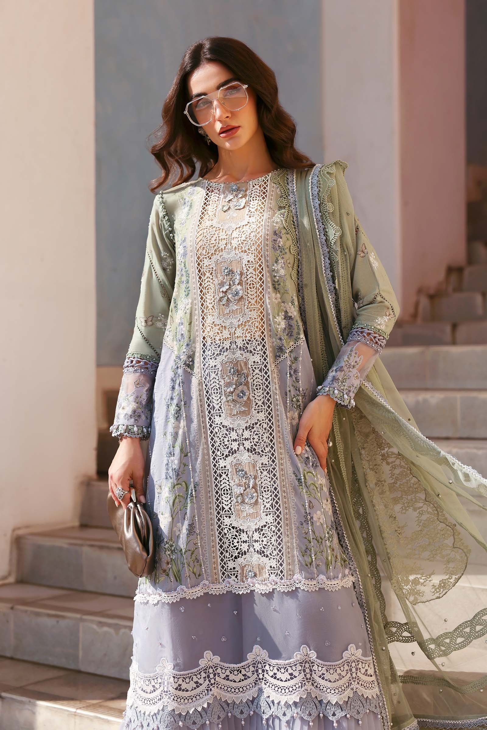Woman in a traditional outfit with intricate patterns standing on steps.