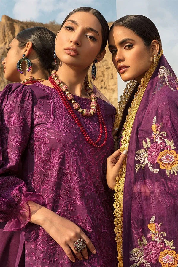 Three models wearing traditional South Asian attire in a desert landscape. The central model wears a deep purple embroidered kurta with a matching sheer embroidered dupatta draped over her shoulder, featuring intricate floral patterns and gold borders.