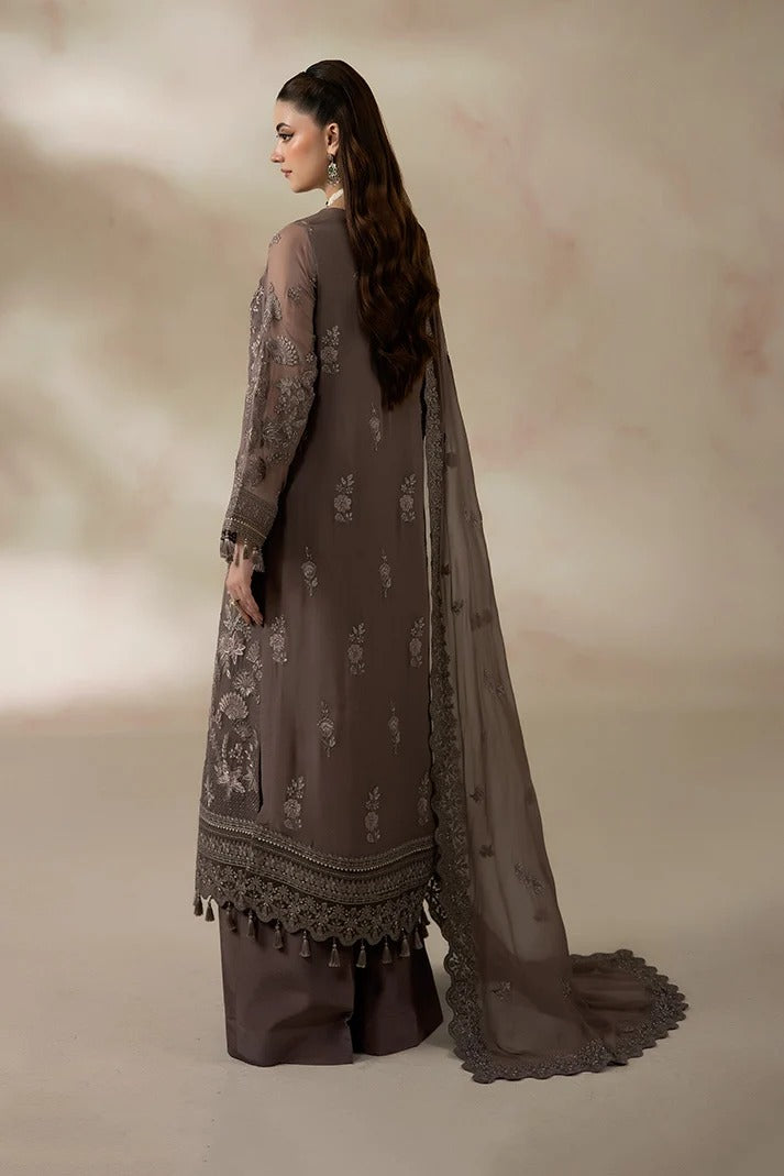 A woman modeling a traditional three-piece salwar kameez suit in taupe brown, shown from the back. The outfit features a long-sleeved embroidered kameez with a matching dupatta and wide-leg trousers, set against a soft beige studio backdrop.