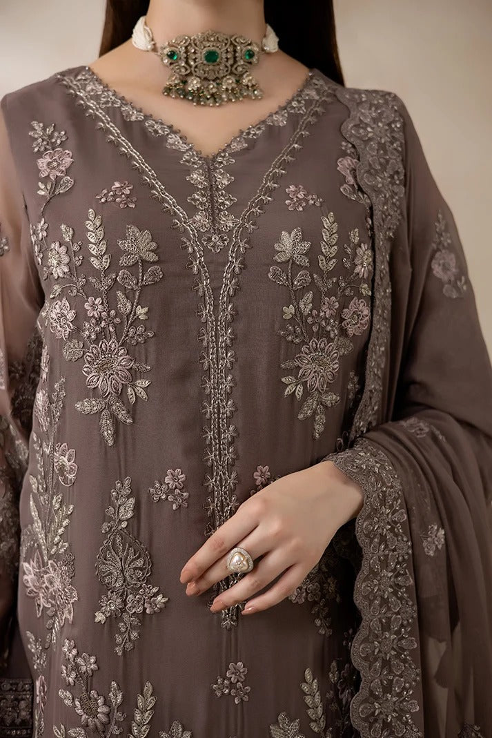 A close-up of a woman wearing an intricately embroidered brown traditional outfit with floral detailing, a matching dupatta, and ornate jewelry.