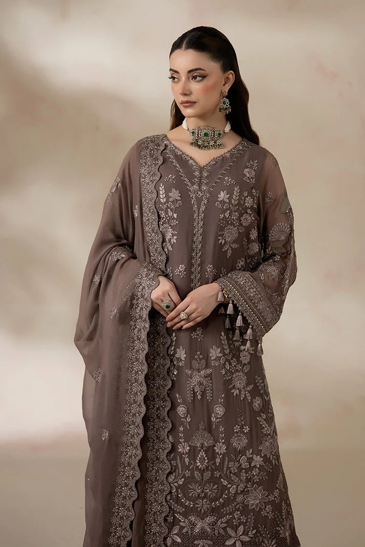 A woman models a traditional long-sleeve embroidered dress in taupe brown with intricate silver floral embroidery and tassel details, paired with a matching sheer dupatta, against a soft beige background.