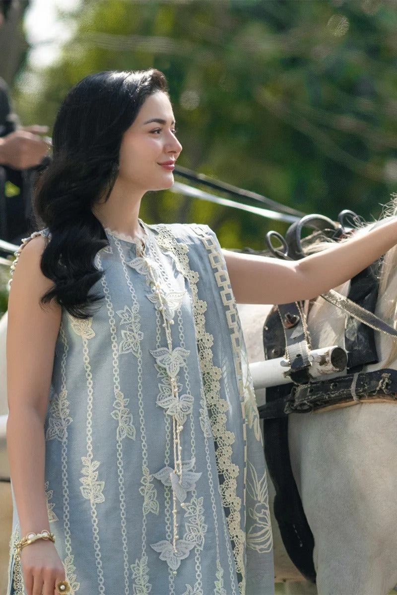 Woman in a light blue embroidered dress standing next to a horse, with a blurred background