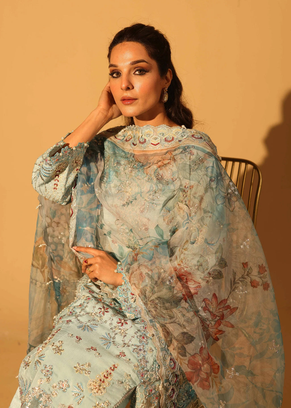 Woman wearing a floral embroidered outfit against a beige background