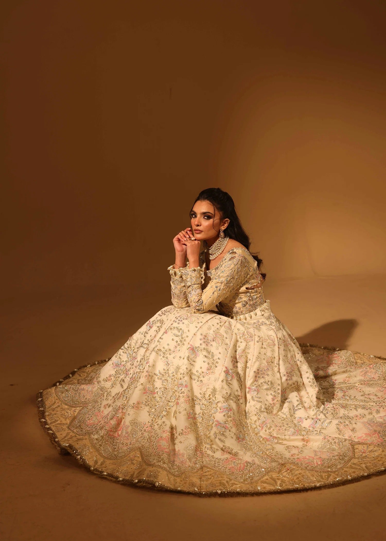 Woman in an ornate dress sitting on a brown background