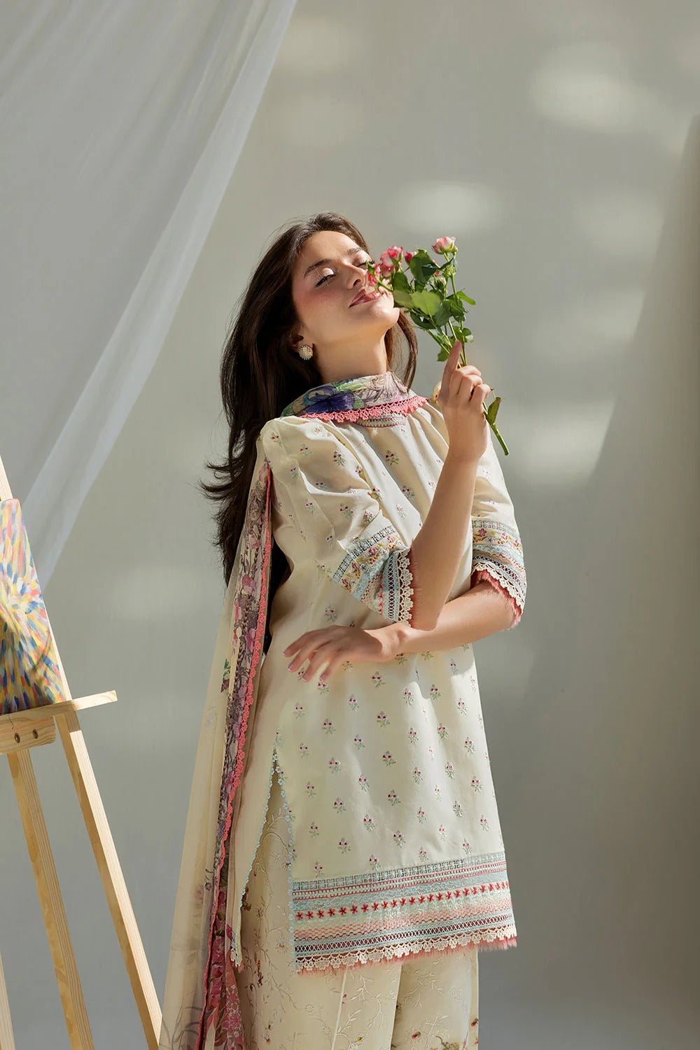 Woman holding flowers in a light room with a neutral background